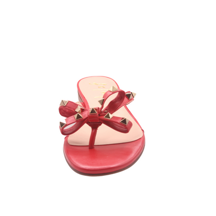 red thong sandal with two bow-shaped straps decorated with gold pyramid studs front view 