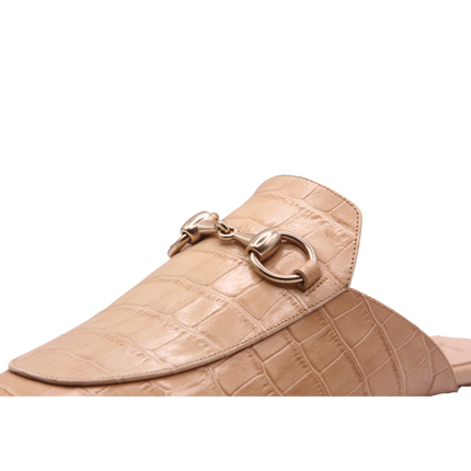 close view of Taupe crocodile-embossed leather mule with a pointed toe, low heel, and a gold buckle detail on the top. 