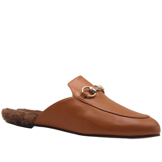 Cognac brown leather mule with a pointed toe, low heel, gold buckle detail on the upper, and a soft fur-lined footbed. angle view 