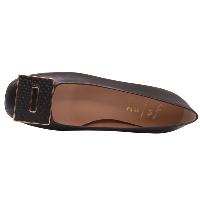 Black leather flat with a square toe, a small heel for slight lift, and a textured black buckle with gold detailing on the toe box top view 
