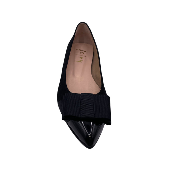 Black suede ballet flat with a pointed patent toe and a layered ribbon bow on the front. front view 