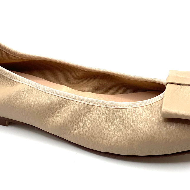 Beige leather ballet flat with a rounded toe and a large folded bow accent on the front. Angle view