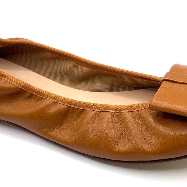 Brown leather ballet flat with a rounded toe and a large folded bow accent on the front. Angle View 