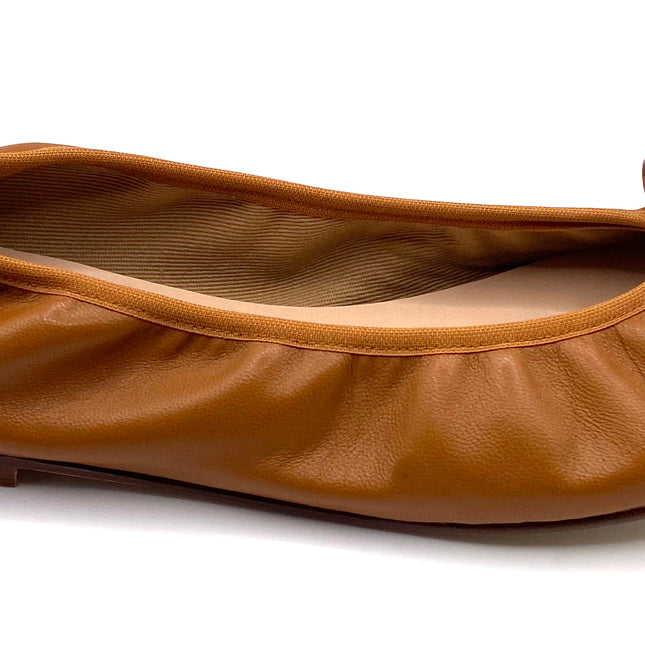Brown leather ballet flat with a rounded toe and a large folded bow accent on the front. Side View