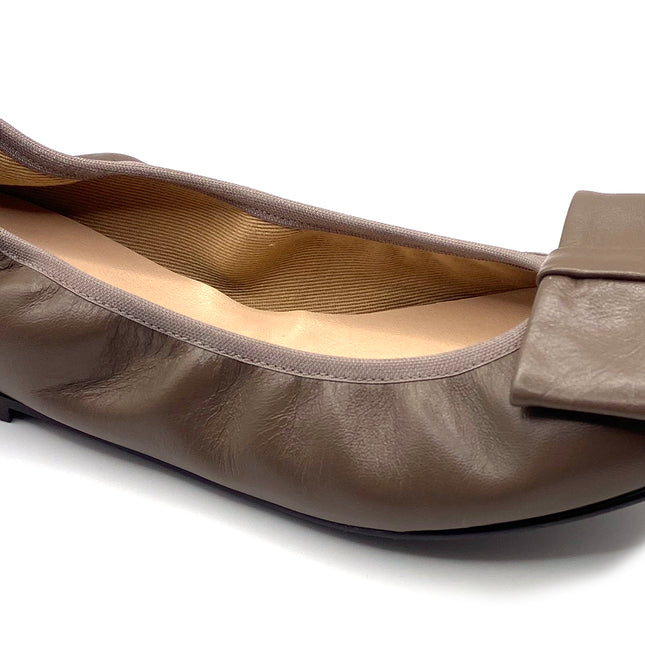 Taupe leather ballet flat with a rounded toe and a large folded bow accent on the front. Angle view