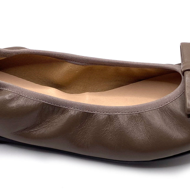 Taupe Leather ballet flat with a rounded toe and a large folded bow accent on the front. Side View 