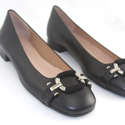 Black leather flat with a square toe, a small heel for slight lift, and a textured black buckle with silver detailing on the toe box both shoes 